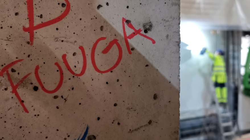 Betonipalkkiin punaisella tussilla kirjoitettu "Fuuga", sivussa taustalla näkyvä turvavarusteisiin pukeutunut rakennusmies.