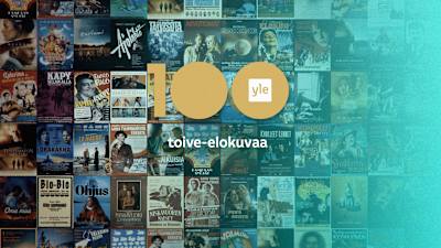 Kuvan taustalla on Ylen 100 -toive-elokuvien kokoelma, joka esittelee monia elokuvia vuosien varrelta.