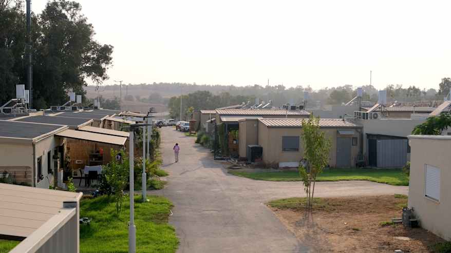 Hiljainen naapurusto täynnä parakkiasuntoja, lapsi kävelee tiellä.