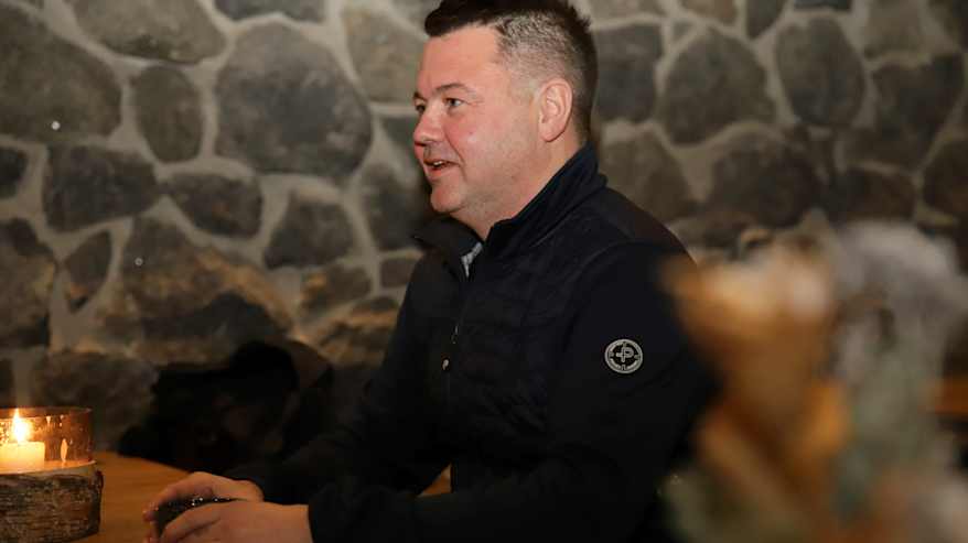 Markus Heiskanen puhuu ravintolapöydän äärellä kahvikuppi käsissään.