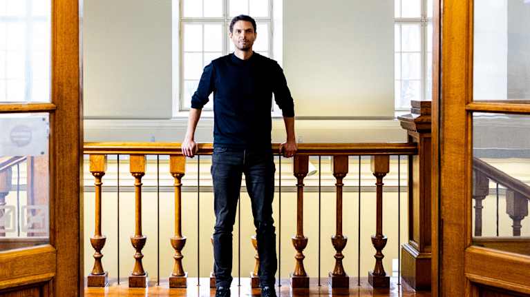 Peter Sarlin seisoo portaiko ylätasanteella, kaunis oviaukko kehystää Sarlinia.