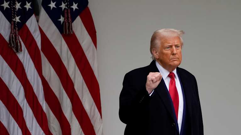 Trump nyrkki pystyssä, vieressä Yhdysvaltain lippu. 