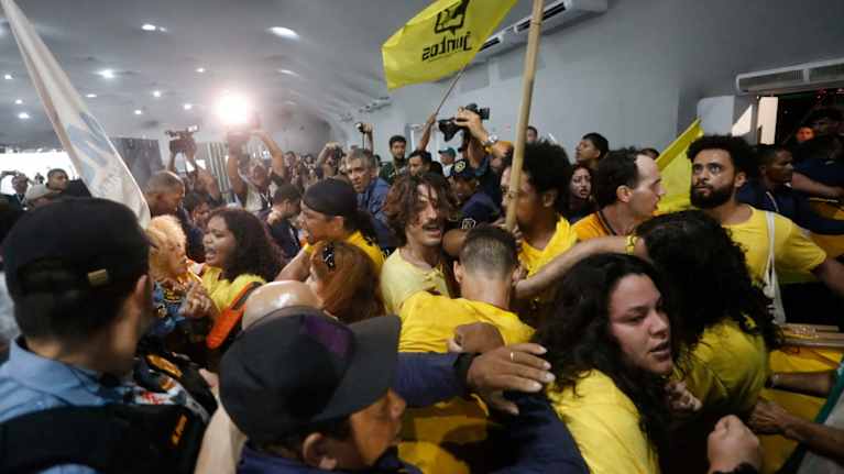 Keltaisiin paitoihin pukeutuneet mielenosoittajat kahinoivat vartijoiden kanssa sisätiloissa.