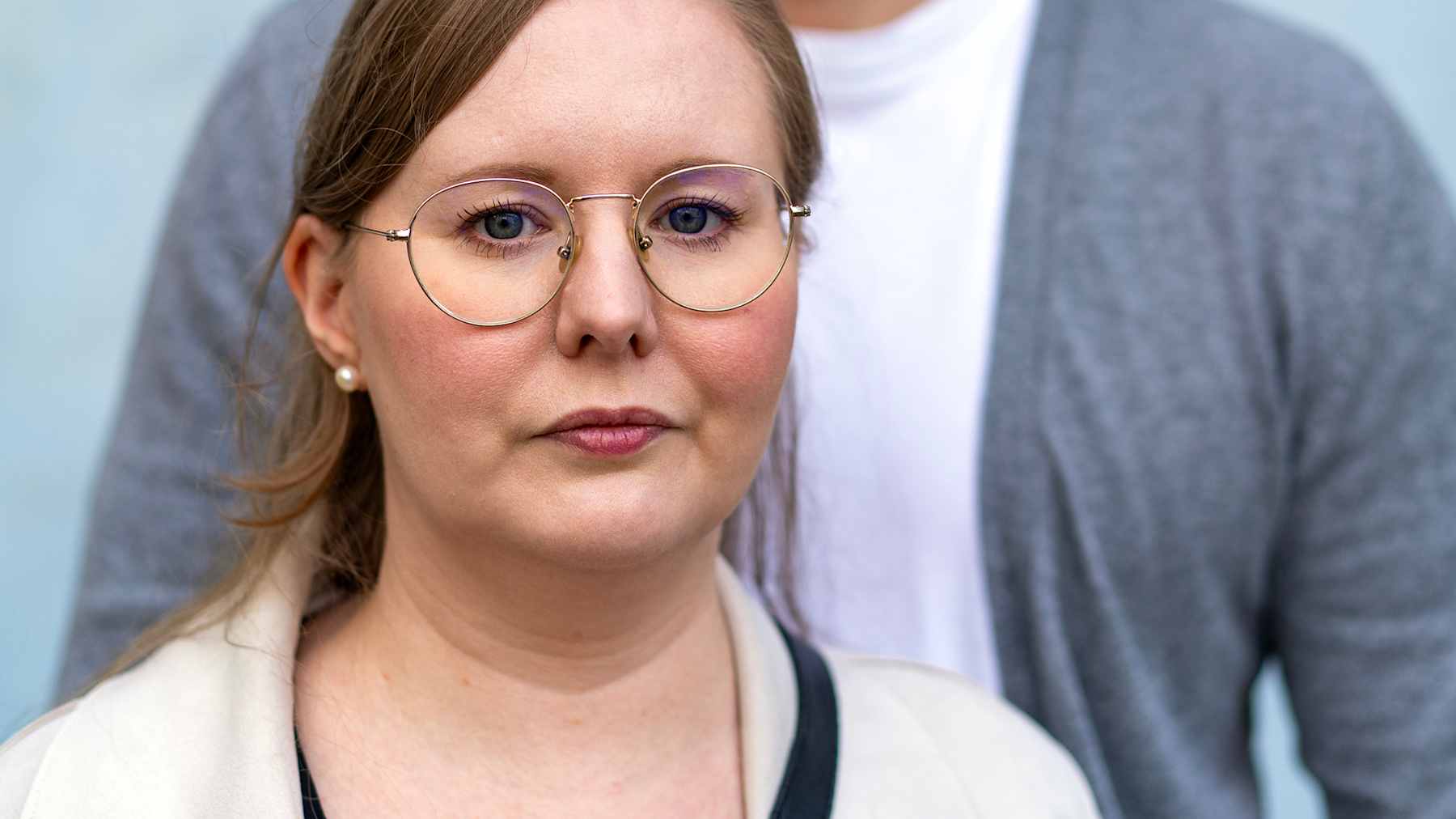 Hanna ja Mikko Poikkilehto seisovat sinisen seinän edessä. Hanna katsoo kameraan, Mikko pois kamerasta.