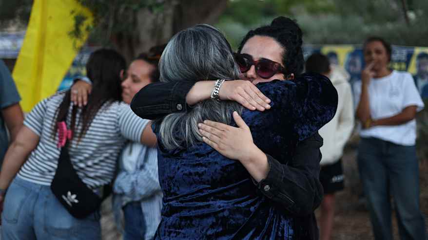 Kaksi naista halaa toisiaan. Taustalla näkyy muita ihmisiä.