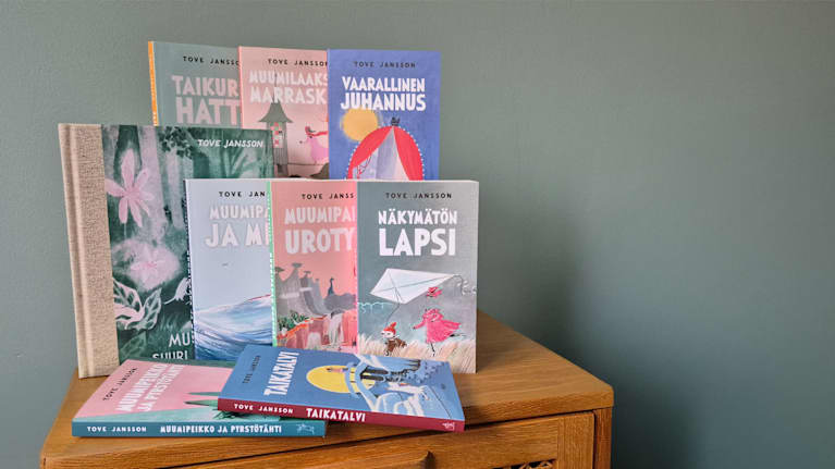 Kuvassa näkyy lipaston päällä kaikki yhdeksän muumiromaania.