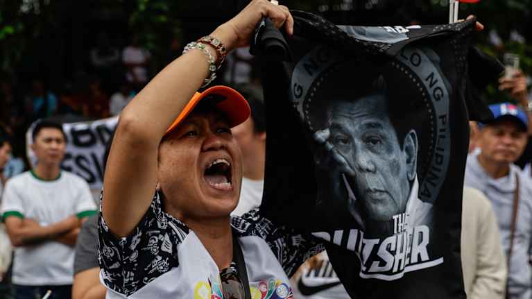 Nainen pitää käsissään presidenttiä vastustavaa mielenosoituslakanaa ja huutaa.