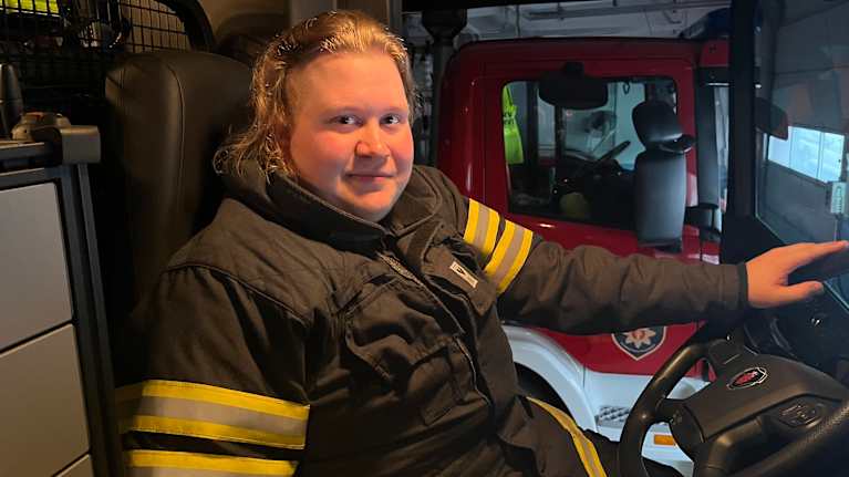 Paloautoaseman työntekijä istuu paloauton ohjaamossa valmiina toimintaan.