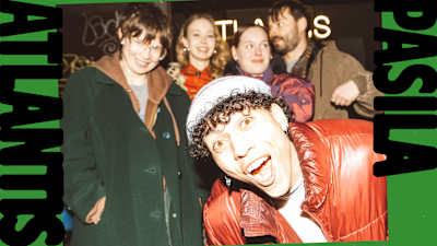 Joukko nuoria poseeraa kameralle ylivalottuneessa kuvassa. Etualalla on kiharahiuksinen nuorimies. Kuvateksti "ATLANTIS PASILA" kehystää koko kuvaa.