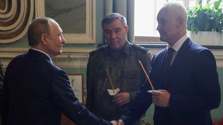 Putin kättelee Belousovia. He ovat tummissa puvuissa. Vieressä seisoo Gerasimov univormussa. Gerasimovilla ja Belousovilla on käsissään  tuohukset-