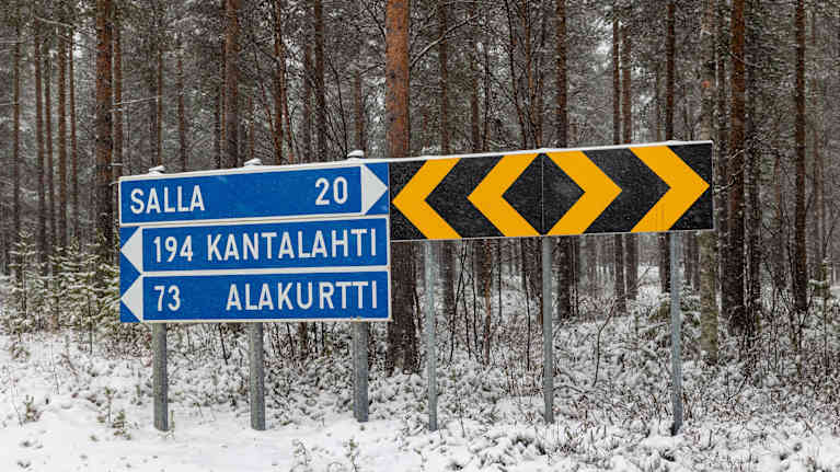 Liikennemerkkejä lumisessa maisemassa. Merkeissä tekstit ALakurtti, Kantalahti Ja salla.