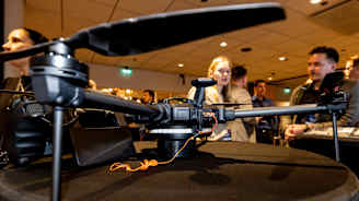 Drooni jonka taustalla näkyy henkilöitä.