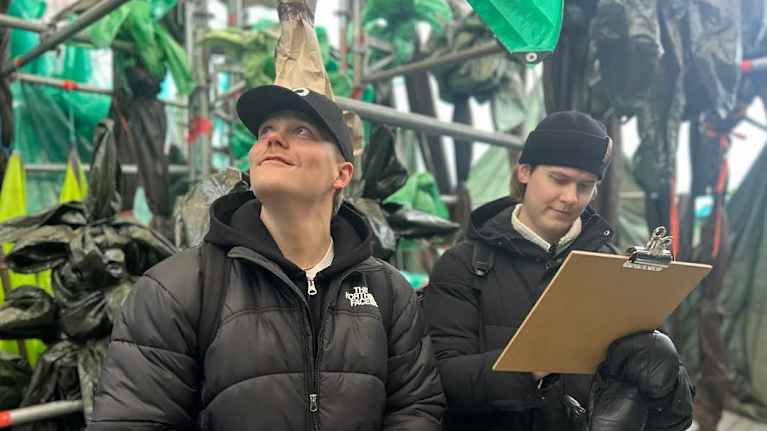 Kaksi nuorta miestä luonnostelee piirroksia taideteoksen sisällä.