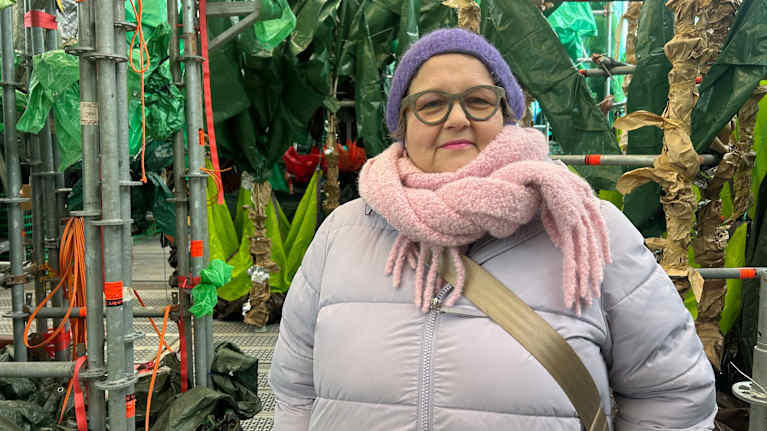 Nainen poseeraa trooppista kasvihuonetta imitoivassa taideteoksessa, 