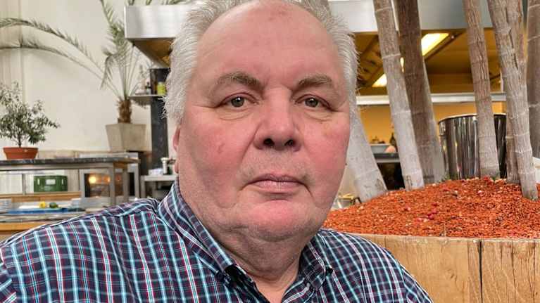 Vanhahko mies katsoo kameraan.