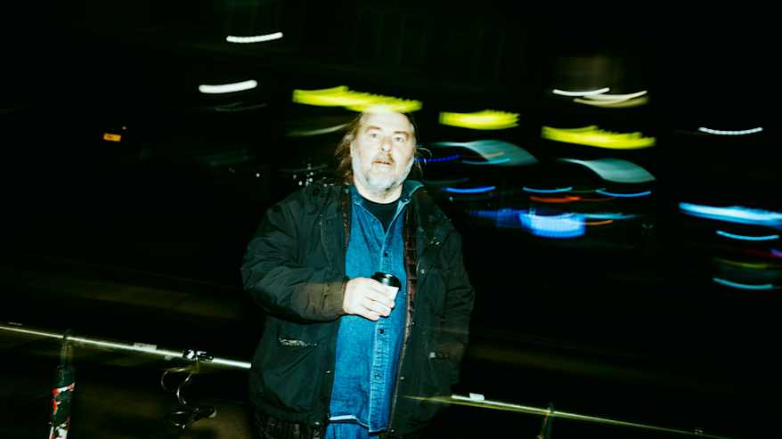 Henkilö nauttii kahvia värikkäiden valojen keskellä pimeässä kaupungissa.