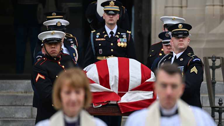 Sotilaat kantavat Yhdysvaltain lippuun kiedottua arkkua ulos kirkosta.