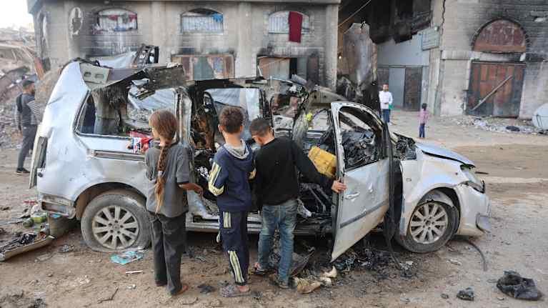 Palestiinalaislapset tutkivat Israelin ilmaiskussa tuhoutunutta autoa.