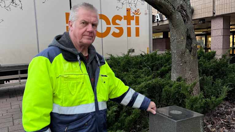 Mies työhaalarissa seisoo kivisen alustan vieressä.