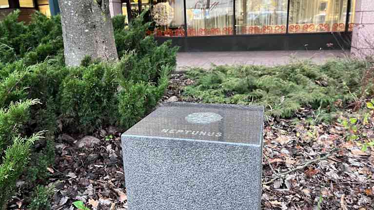 Kirjaston edessä on kivialusta, jossa lukee Neptunus. Alustassa ollut planeetta-teos on kadonnut.