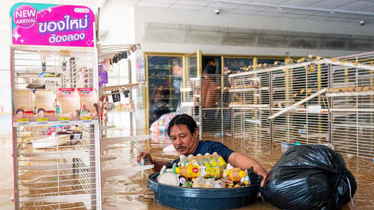 Henkilö kahlaa tulvavedessä myymälän sisällä.