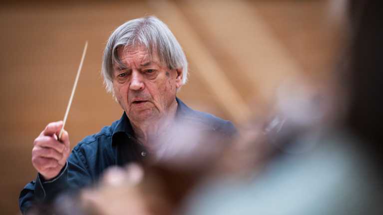 Mies heiluttaa tahtipuikkoa.