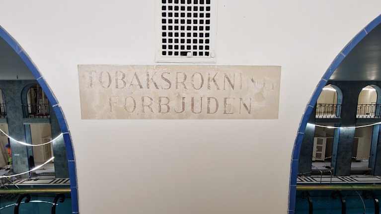 Remontissa seinästä paljastunut vanha tupakoinnin kieltävä kyltti Yrjönkadun uimahallin sisäseinässä.