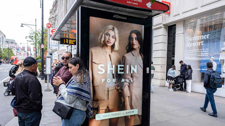 Vaatteita mainostava mainostaulu bussipysäkillä.