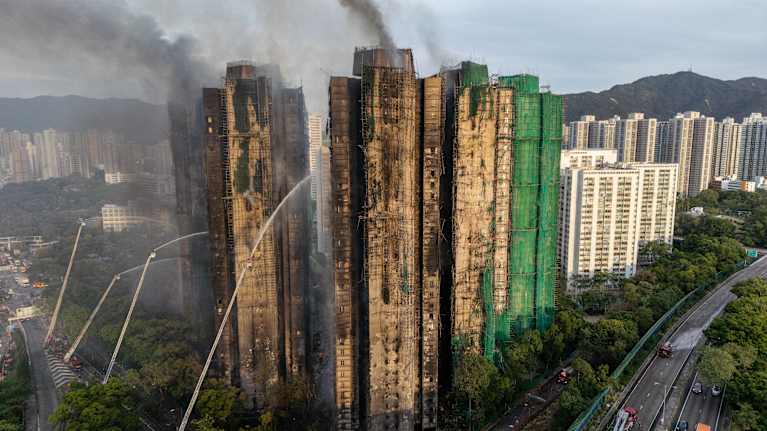 Kuvattuna ylhäältäpäin savuavat rakennukset, joihin suihkutetaan useasta kohdasta vettä.