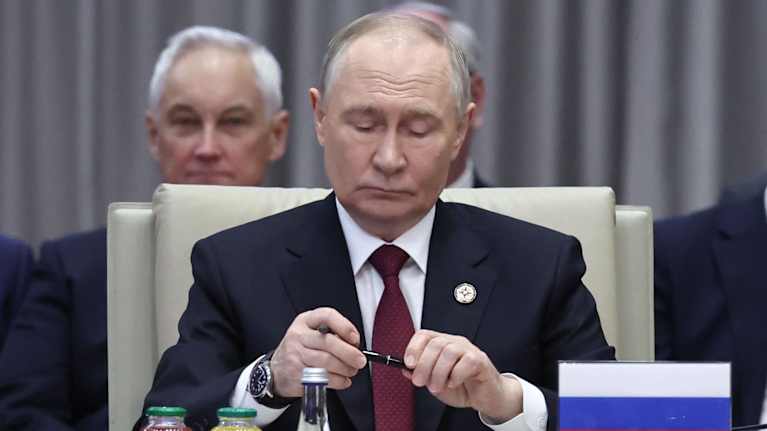 Vladimir Putin pitelee kynää käsissään. 