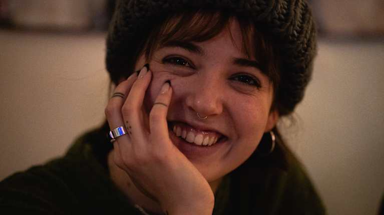 Milla Lähtevänoja katsoo käsi poskella kameraan ja hymyilee.