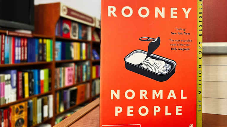 Normal people -kirja esillä. Taustalla on näkyy kirjahyllyä.