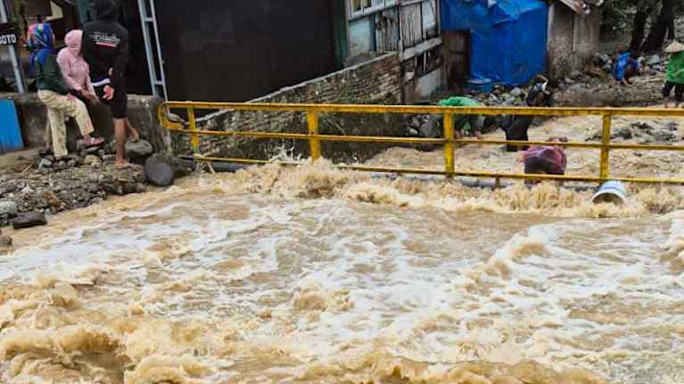 Ruskea tulvavesi virtaa kuohuen talon ohi.