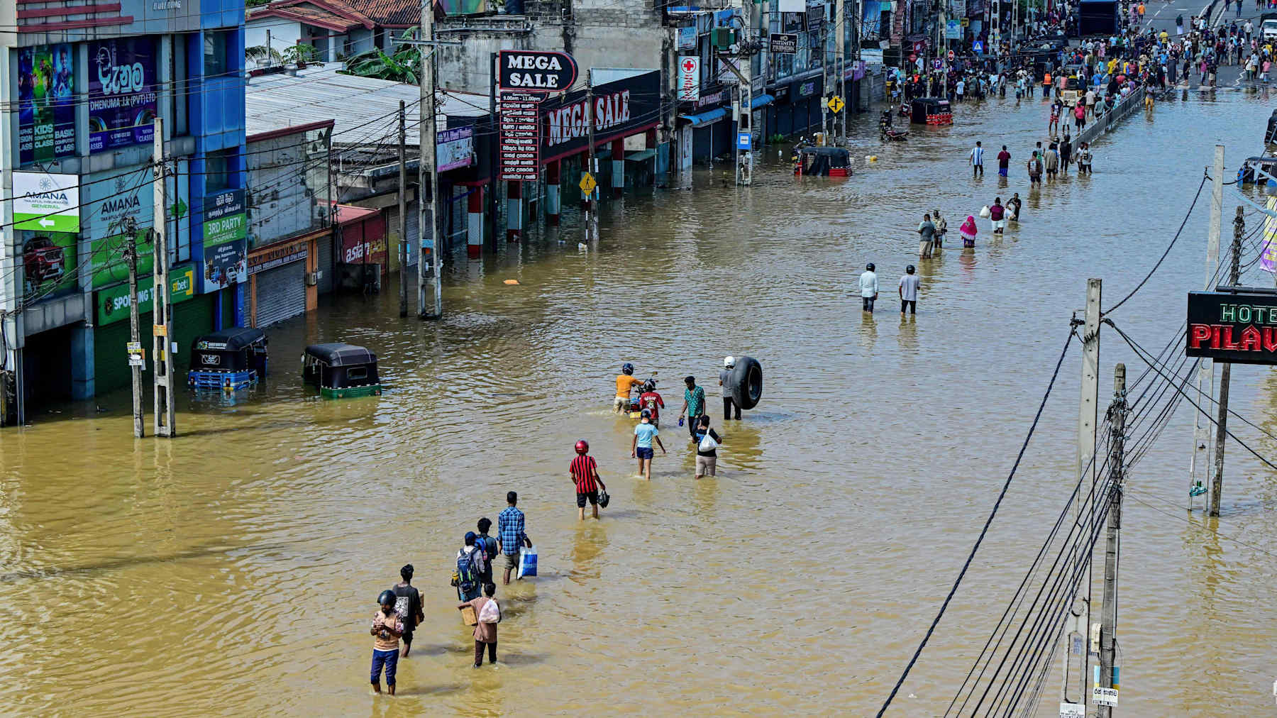 Ihmiset kävelevät kadulla, joka on veden peitossa.