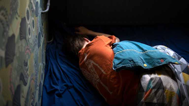 Nuori makaa sängyssä.