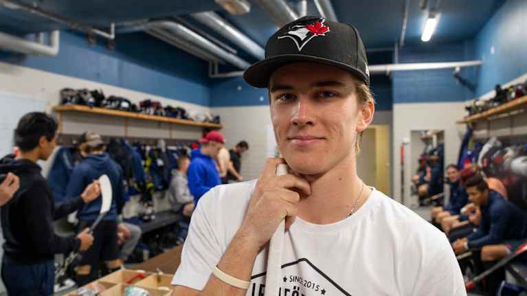 Veeti Miettinen jääkiekkomailan kanssa pukuhuoneessa.