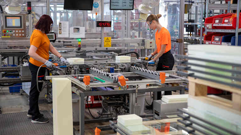 kaksi Lumonin työntekijää käsittelee parvekelaseja Kouvolan tehtaalla