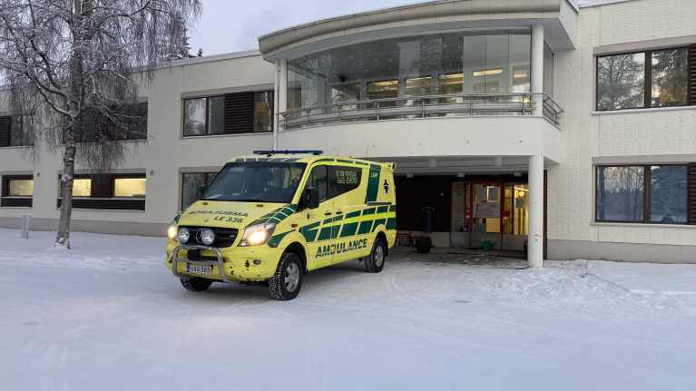 Ambulanssi Ivalon terveyskeskuksen takaoven edessä.