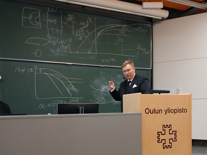Mies%20pit%E4m%E4ss%E4%20esitelm%E4%E4%20yliopiston%20luokkahuoneessa%20liitutaulun%20edess%E4.