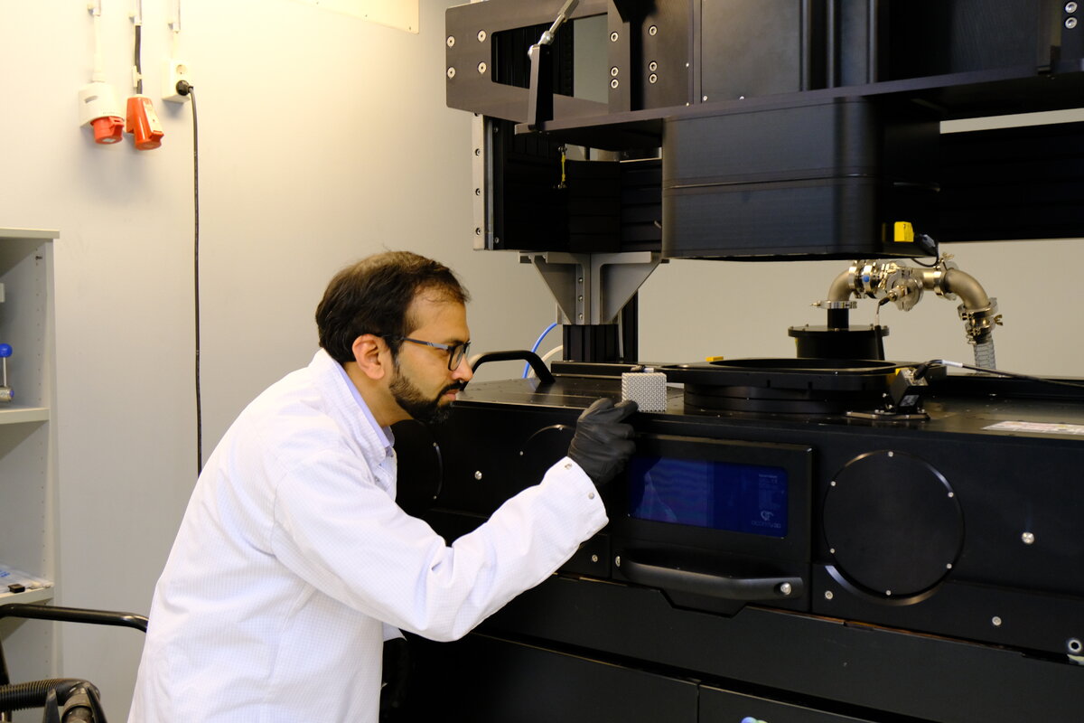 Hankkeen koordinaattori, apulaisprofessori Ashish Ganvir tarkastelee Turun yliopiston metallintulostusjärjestelmällä 3D-tulostettua metalliosaa. Laitteisto on olennainen osa hankkeen teknologisena perustana toimivaa tuotantoalustaa.