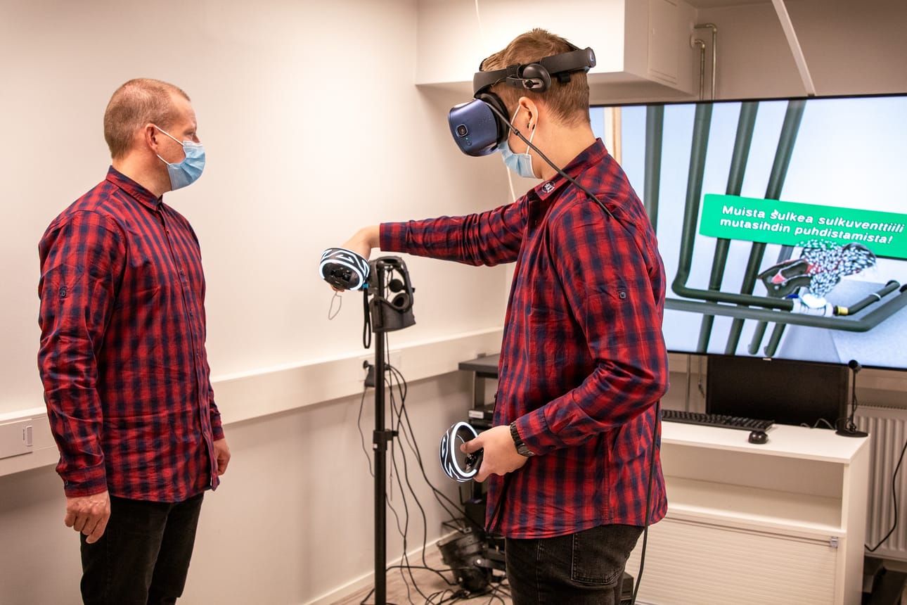 DUKE-hankkeen koodaaja Severi Kangas (oik.) esittelee, miten VR-teknologian avulla voidaan harjoitella ilma-vesilämpöpumpun huoltotöitä. Vasemmalla projektipäällikkö Ari Kumpula.