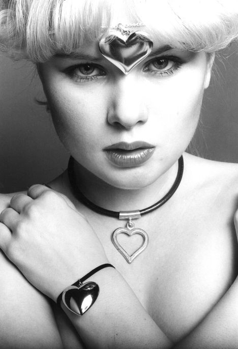 Sano se sydämin. Ja monin sydämin. Mannekiinin otsalla on jykevä, tukeva hopeanvärinen sydän. Stockmann 18 mk. Kaulassa on hassu piparimuotti, siro sinänsä. Sylvia Kemikalia 29 mk. Ranteeseen on sitaistu hellyttävän pullea kultasydän. Valintatalo 14,70 mk.