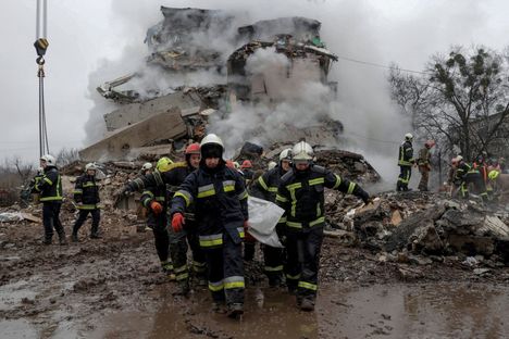 Pelastajat kantavat ruumista, joka löytyi asuinrakennuksen raunioista Poltavassa.