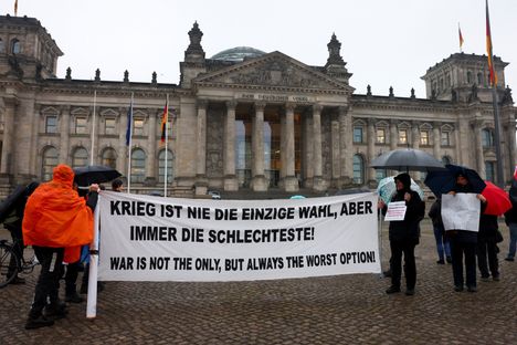 Useat aktivistit pitävät suurta valkoista banderollia, jossa lukee saksaksi ja englanniksi sodanvastainen lause, "Sota ei ole ainoa, mutta aina huonoin vaihtoehto!”