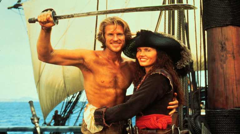 Still-kuva elokuvasta Kurkunleikkaajien saari. Kuvassa näyttelijät Matthew Modine ja Geena Davis merirosvolaivan kannella.