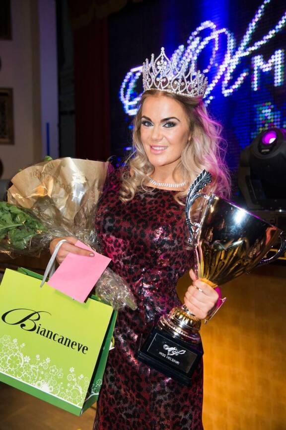 Rosanna poseeraa kameralle Miss Helsinki -kruunu pääsään käsissään pokaali, kukkakimppu ja palkintokassi.