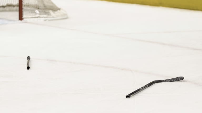 Katkennut jääkiekkomaila jään pinnalla.