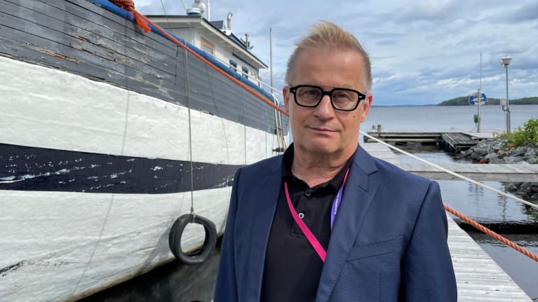 Silmälasipäinen mies seisoo venelaiturilla.