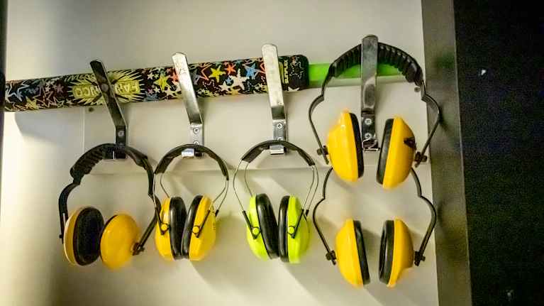 Aistiyliherkille oppilaille tarkoitettuja kuulosuojaimia luokan seinällä.