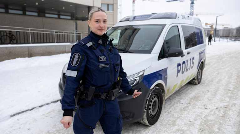 Poliisina työskentelevä kilpauimari Veera Kivirinta poseeraa poliisiauton edessä.